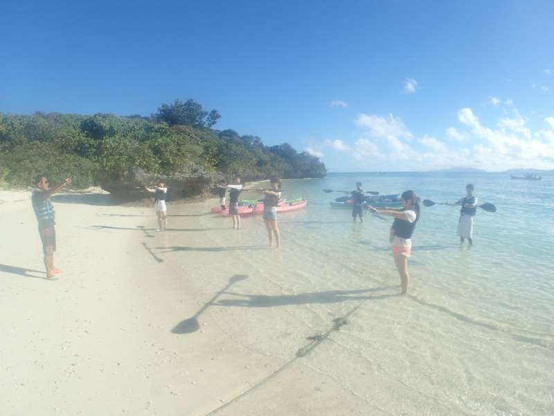 川平湾のビーチでカヤックの漕ぎ方の練習をしているツアー客