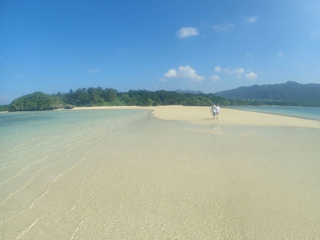 川平湾の無人島ビーチを歩くツアー客